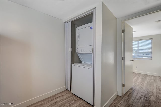 washroom with stacked washer / dryer and light hardwood / wood-style flooring