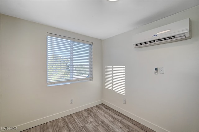 empty room with light hardwood / wood-style floors and an AC wall unit