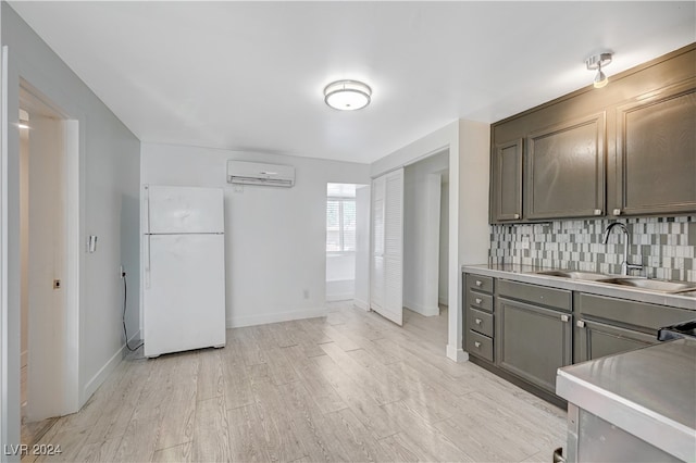 kitchen featuring a wall mounted AC, light hardwood / wood-style flooring, backsplash, sink, and white refrigerator