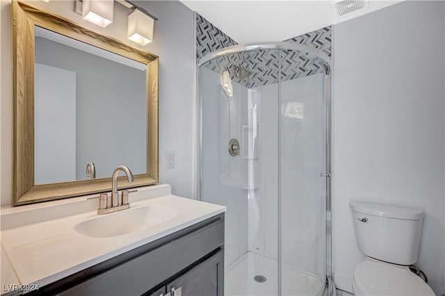 bathroom featuring toilet, vanity, and a shower with door