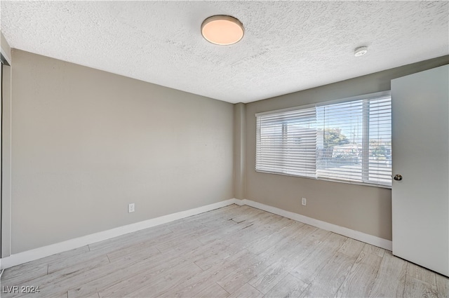 unfurnished room featuring light hardwood / wood-style flooring and a textured ceiling