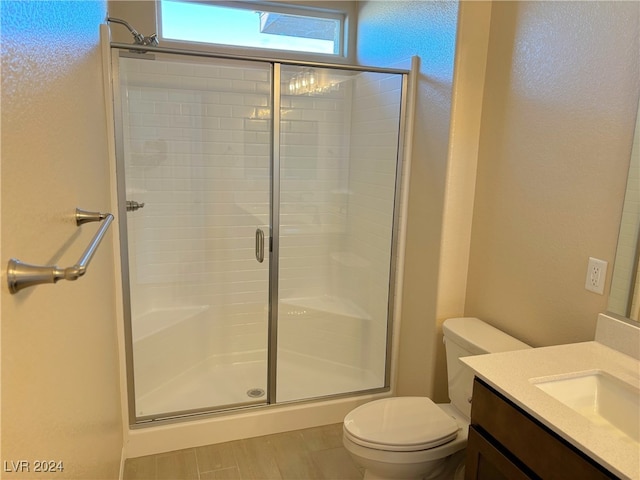 bathroom featuring vanity, toilet, and a shower with shower door