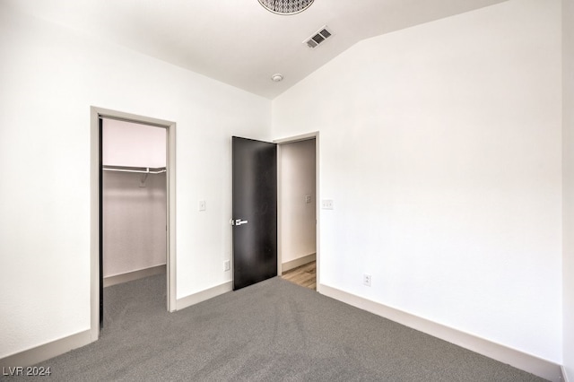 unfurnished bedroom with a spacious closet, light carpet, a closet, and lofted ceiling