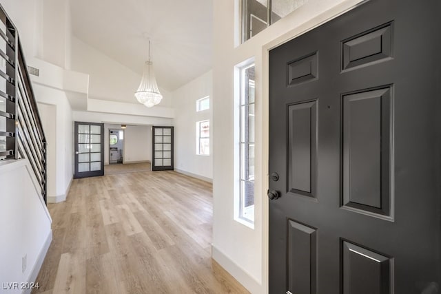 foyer entrance featuring light hardwood / wood-style floors, an inviting chandelier, and high vaulted ceiling