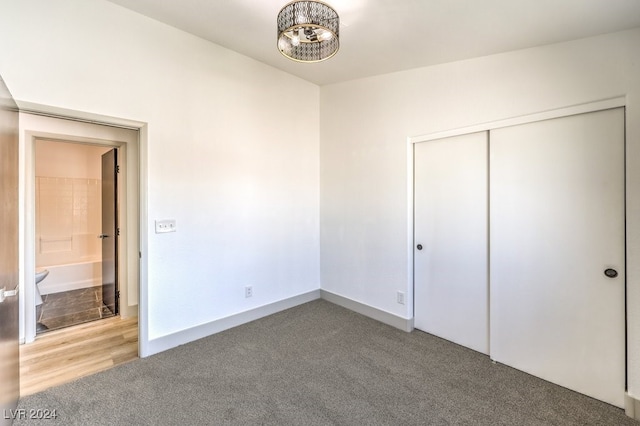 unfurnished bedroom featuring a closet, carpet floors, and ensuite bath