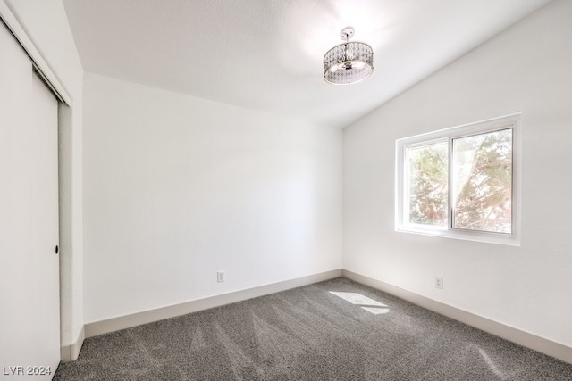 unfurnished bedroom featuring lofted ceiling, a closet, and carpet