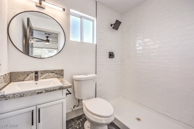 bathroom featuring vanity, a tile shower, toilet, and ceiling fan