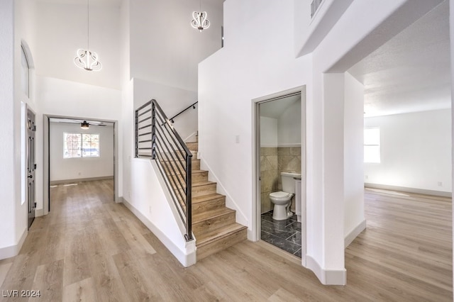 stairway featuring ceiling fan, a towering ceiling, and hardwood / wood-style floors