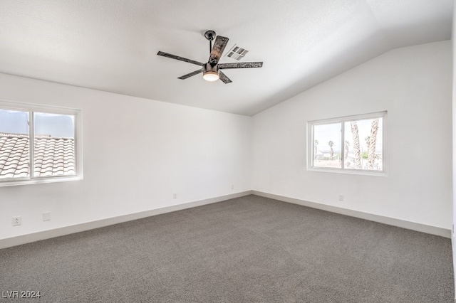 spare room featuring a healthy amount of sunlight, ceiling fan, carpet, and vaulted ceiling