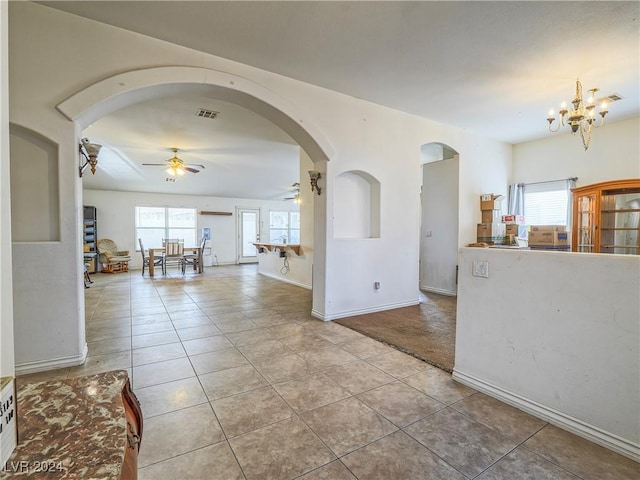 interior space featuring light tile patterned flooring, plenty of natural light, and ceiling fan with notable chandelier