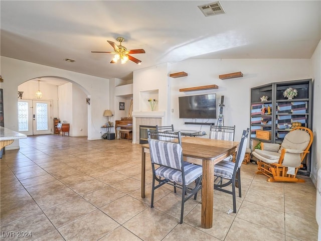 dining room featuring french doors, vaulted ceiling, light tile patterned floors, a tile fireplace, and ceiling fan