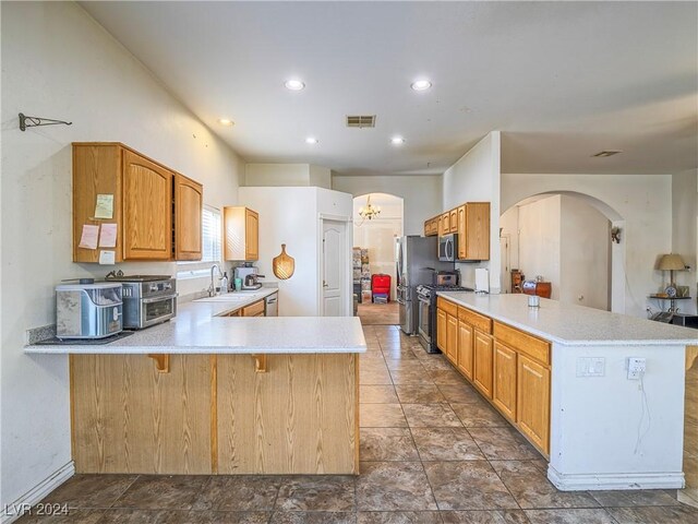 kitchen featuring stainless steel appliances, sink, an inviting chandelier, and kitchen peninsula