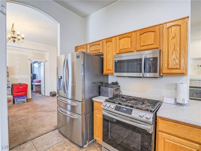 kitchen featuring a notable chandelier, light colored carpet, and stainless steel appliances