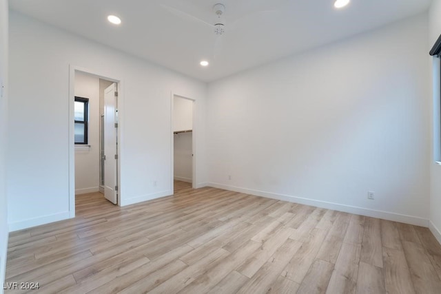 unfurnished bedroom with a closet, a walk in closet, and light wood-type flooring