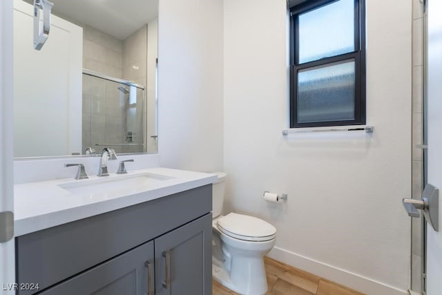 bathroom featuring vanity, a shower with shower door, wood-type flooring, and toilet