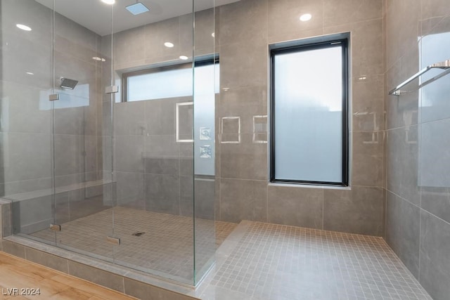 bathroom with a shower with door and tile walls