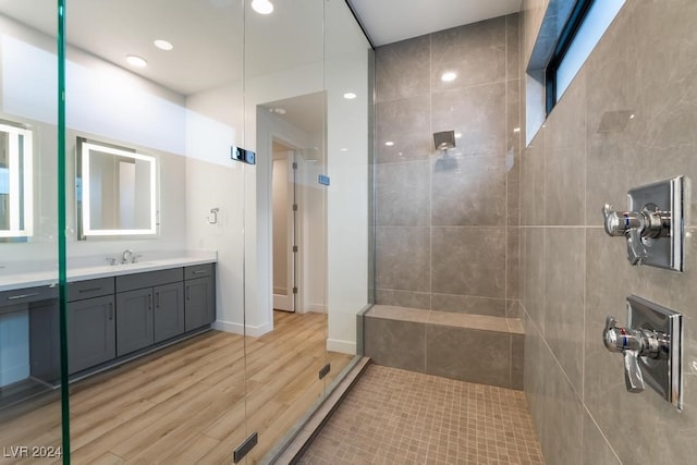 bathroom featuring vanity, wood-type flooring, and tiled shower