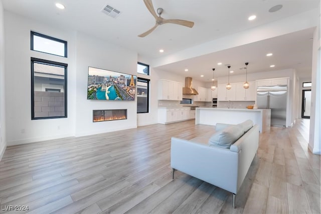 living room with plenty of natural light, light wood-type flooring, and ceiling fan