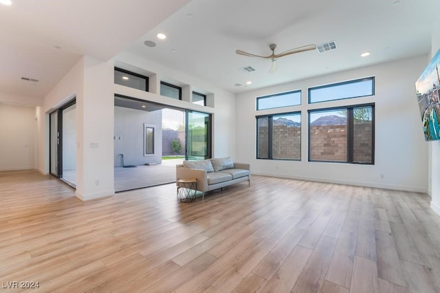 unfurnished room with ceiling fan, light wood-type flooring, and a wealth of natural light