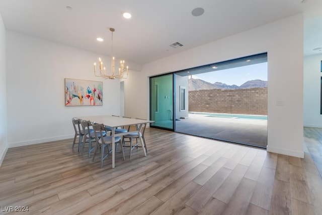 dining area featuring an inviting chandelier, light hardwood / wood-style flooring, and a mountain view