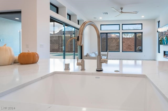 details featuring sink, light stone countertops, and ceiling fan