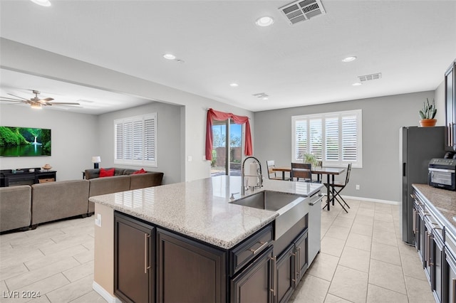 kitchen with dishwasher, sink, ceiling fan, dark brown cabinets, and light stone counters