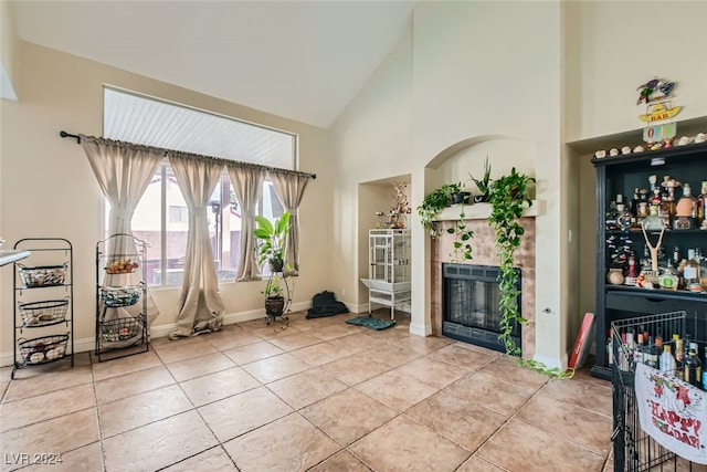 living room with high vaulted ceiling, a tile fireplace, and tile patterned floors