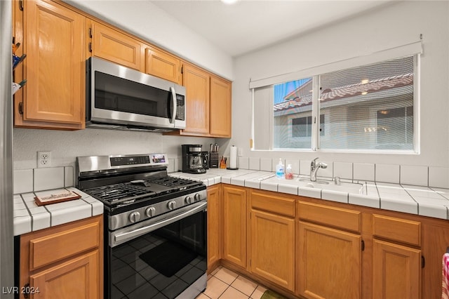 kitchen featuring light tile patterned flooring, tile counters, and stainless steel appliances