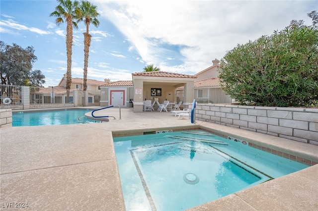 view of swimming pool featuring a community hot tub and a patio area