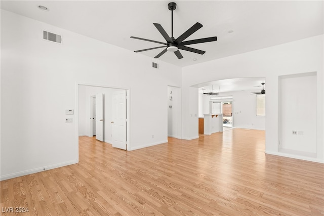 unfurnished living room with ceiling fan with notable chandelier and light wood-type flooring