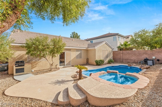 rear view of property featuring an in ground hot tub and a patio