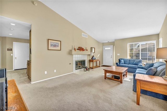 living room with light colored carpet, lofted ceiling, and a tiled fireplace