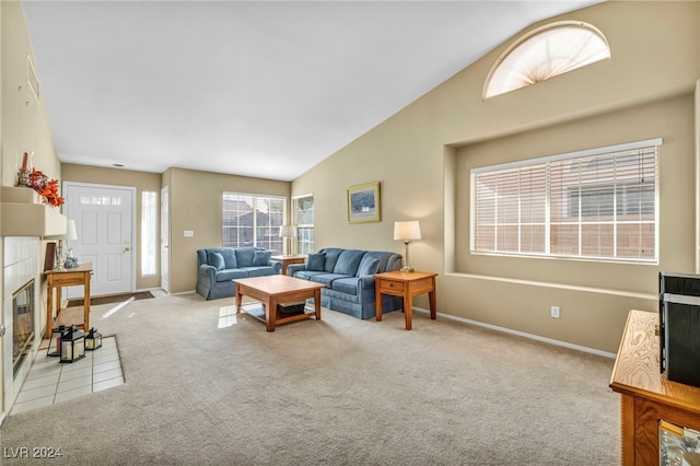 living room with a tiled fireplace, light carpet, and vaulted ceiling