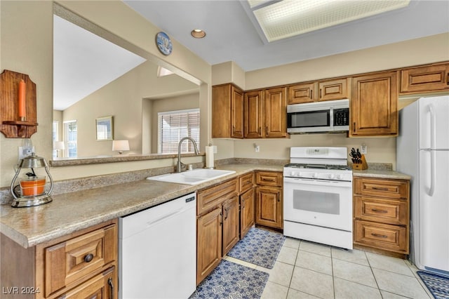 kitchen with lofted ceiling, white appliances, sink, light tile patterned flooring, and kitchen peninsula