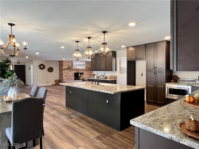 kitchen featuring dark hardwood / wood-style floors, sink, pendant lighting, and an island with sink