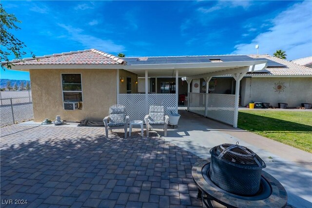 rear view of property featuring a patio, an outdoor fire pit, and a lawn