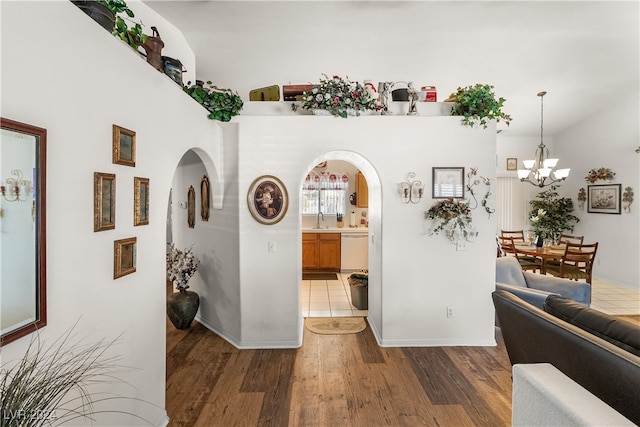 hall with a chandelier, dark hardwood / wood-style flooring, vaulted ceiling, and sink