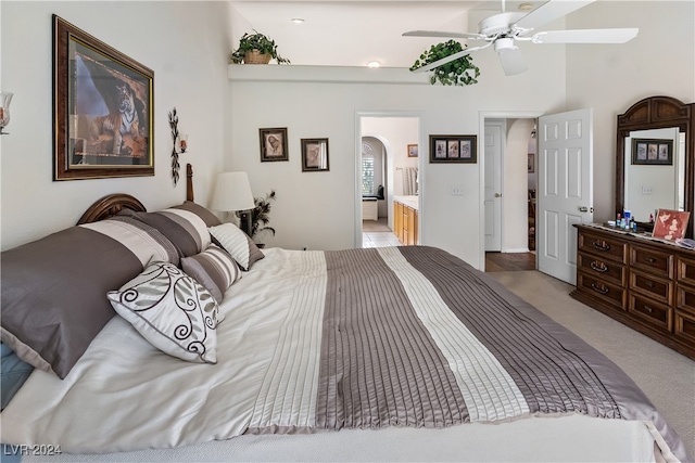 bedroom featuring ensuite bathroom, light carpet, and ceiling fan