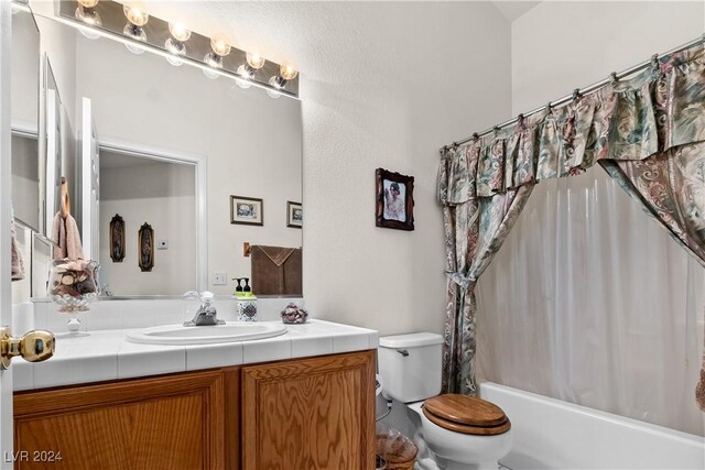 full bathroom featuring vanity, shower / bath combination with curtain, and toilet