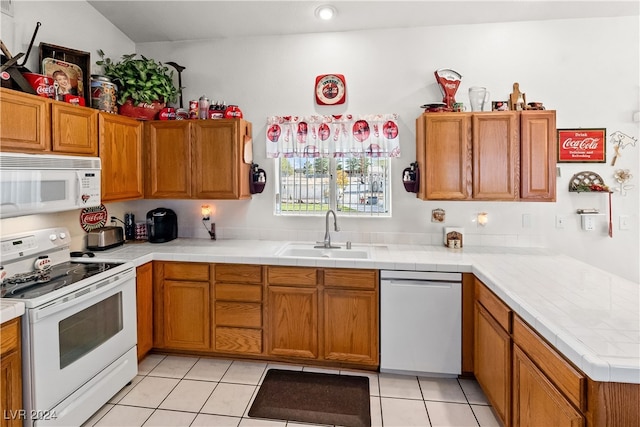 kitchen with white appliances, vaulted ceiling, sink, light tile patterned floors, and tile countertops