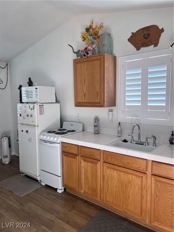 kitchen with white appliances, vaulted ceiling, dark wood-type flooring, and sink