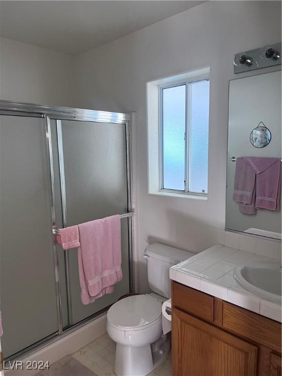 bathroom with a shower with door, vanity, and toilet