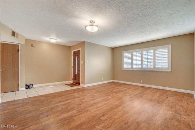 empty room with a textured ceiling and light wood-type flooring