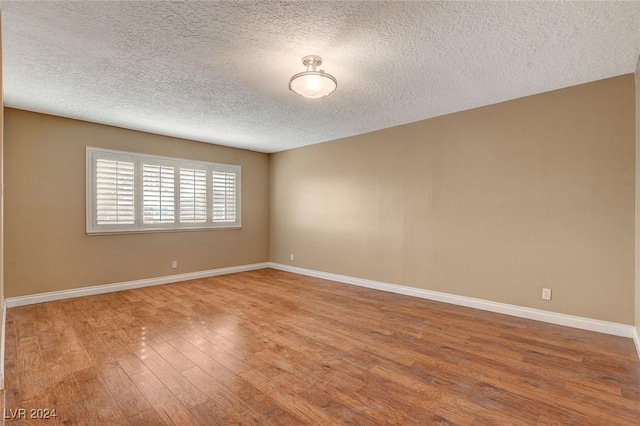 empty room featuring a textured ceiling and hardwood / wood-style flooring