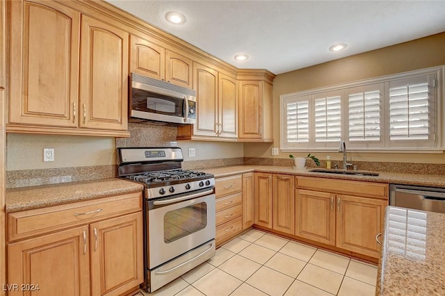 kitchen featuring sink, light tile patterned floors, light brown cabinetry, appliances with stainless steel finishes, and light stone counters