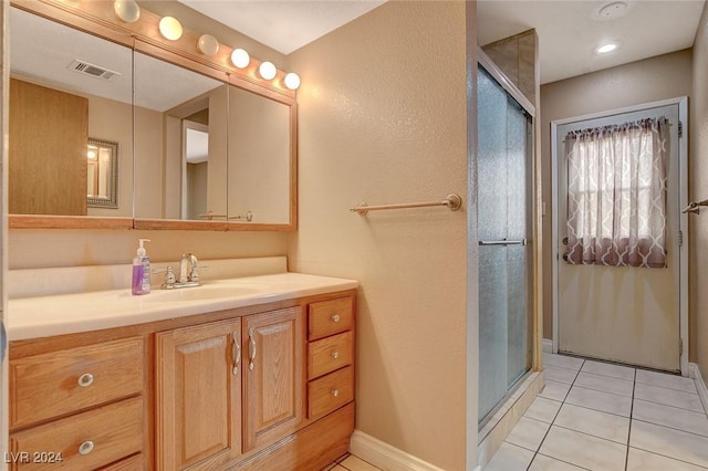 bathroom featuring tile patterned flooring, vanity, and an enclosed shower