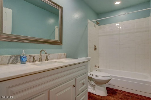 full bathroom featuring vanity, tiled shower / bath combo, hardwood / wood-style flooring, and toilet