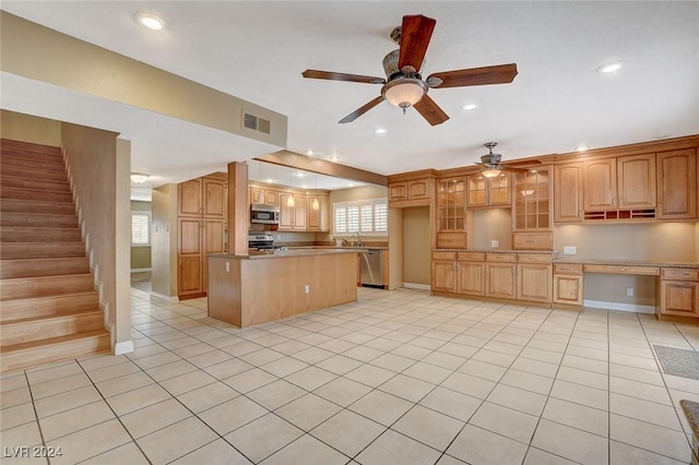 kitchen featuring ceiling fan, a center island, stainless steel appliances, light tile patterned flooring, and built in desk