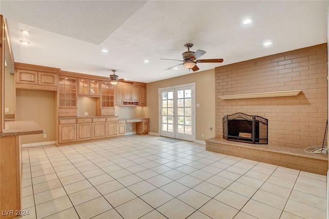 unfurnished living room featuring ceiling fan, a fireplace, and light tile patterned flooring