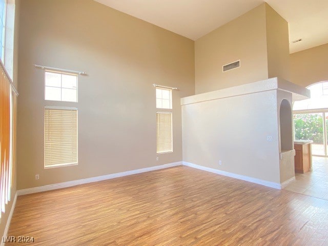 unfurnished room featuring a towering ceiling and light wood-type flooring